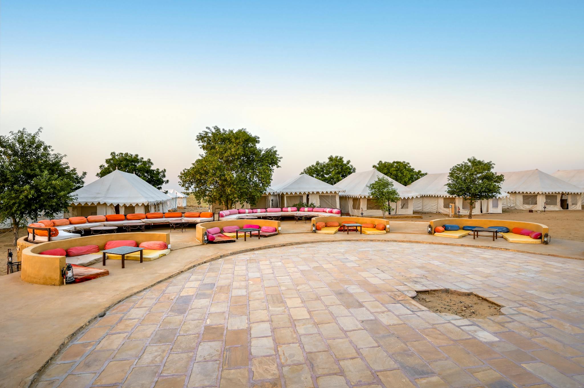 Vibrant desert camp with luxury tents and colorful seating in Jaisalmer, India.